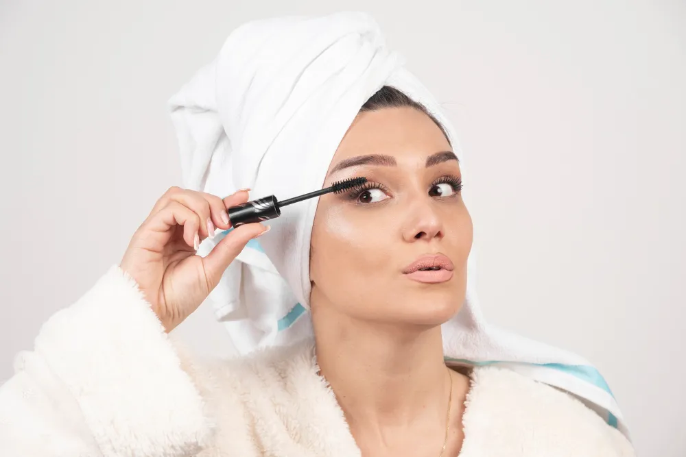 portrait-woman-wrapped-white-towel-applying-mascara