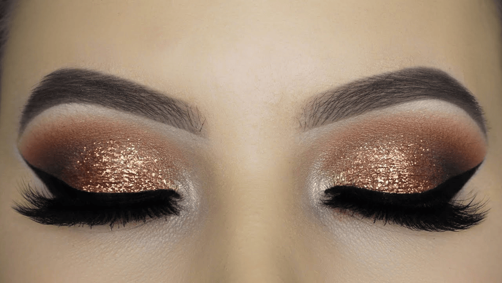 An elegant makeup look featuring gold eye makeup and shimmering highlights.
